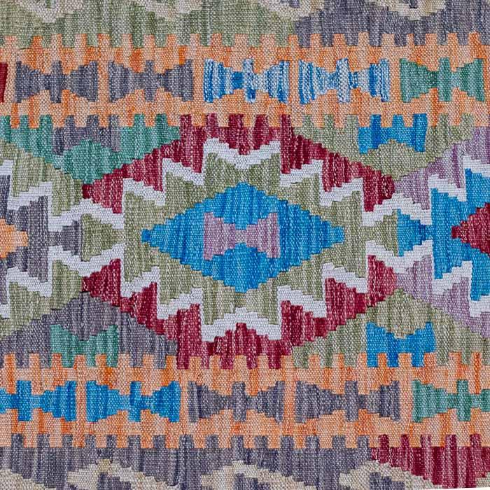 Peça têxtil exclusiva tecida manualmente no Afeganistão com tons de azul, vermelho e ocre.