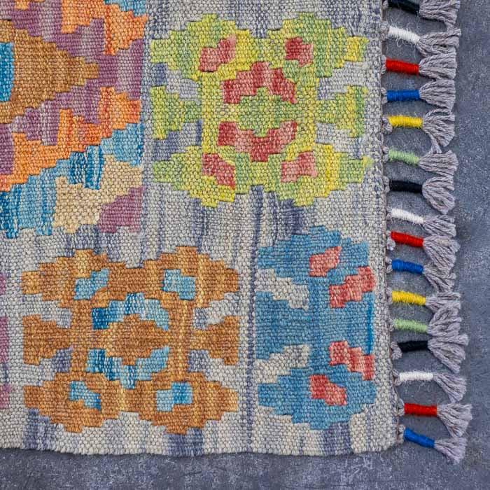 Peça têxtil exclusiva tecida manualmente no Afeganistão com tons de azul e ocre.