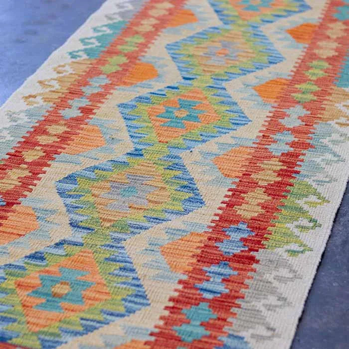 Tapete Kilim afegão de trama plana decorando corredor com paredes claras.