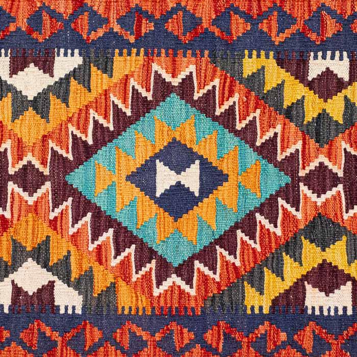 Passadeira artesanal Kilim do Afeganistão apresentando grafismos étnicos multicoloridos sobre trama manual plana de lã.
