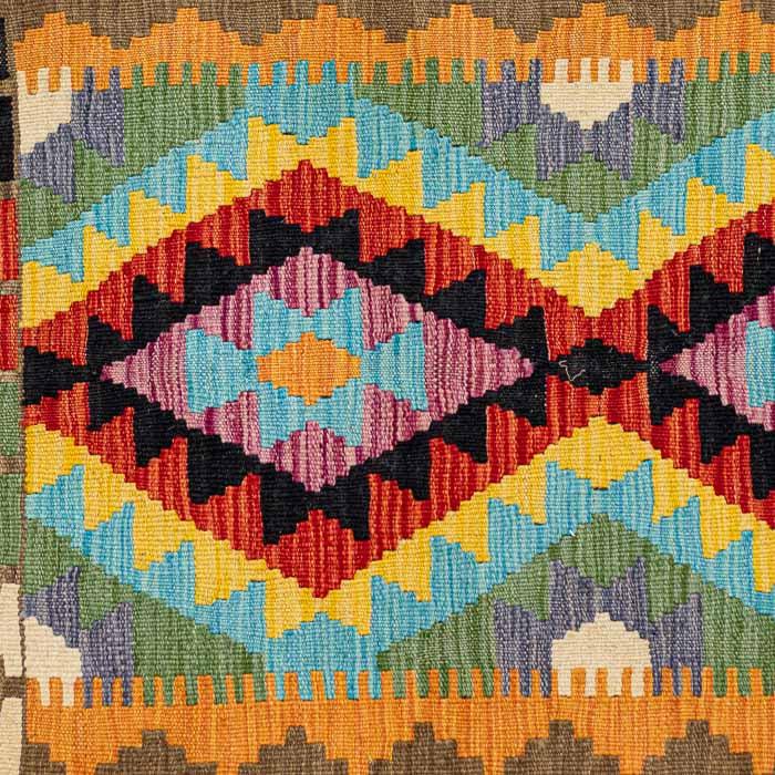 Passadeira étnica Kilim afegã com losangos multicoloridos e franjas artesanais em plano detalhado.