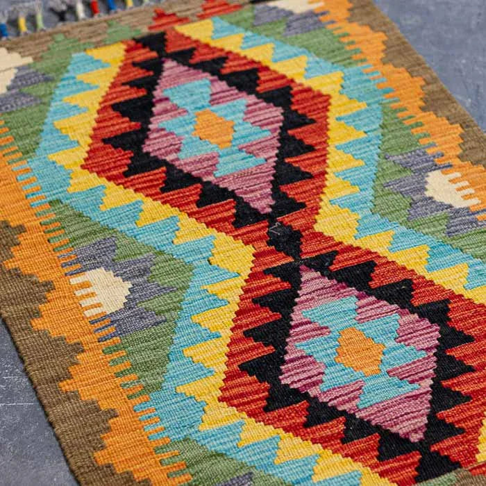 Decoração rústica de luxo com pequeno tapete Kilim colorido sobre piso de madeira clara.