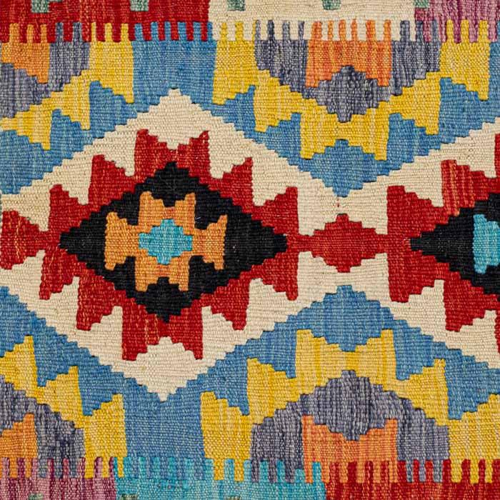 Tapete artesanal Kilim do Afeganistão com grafismos geométricos étnicos coloridos e técnica de tecelagem plana manual.