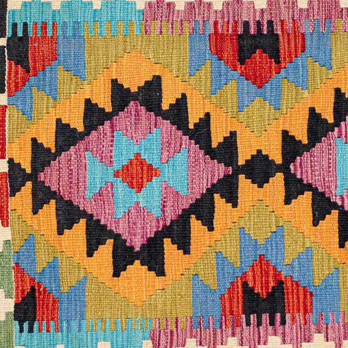 Tapete artesanal Kilim do Afeganistão apresentando grafismos étnicos simétricos sobre trama manual plana de lã natural.