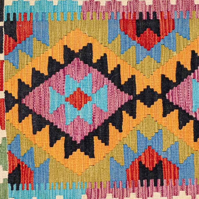 Tapete artesanal Kilim do Afeganistão apresentando grafismos étnicos simétricos sobre trama manual plana de lã natural.