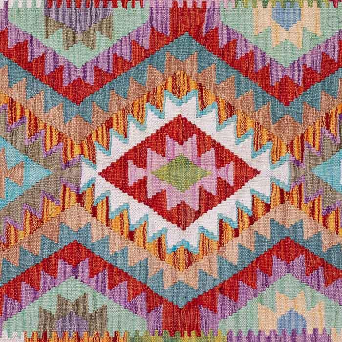 Tapete artesanal Kilim do Afeganistão com grafismos étnicos simétricos sobre trama manual plana de lã natural.