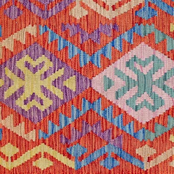 Tapete artesanal Kilim do Afeganistão apresentando grafismos étnicos simétricos sobre trama manual plana de lã natural.