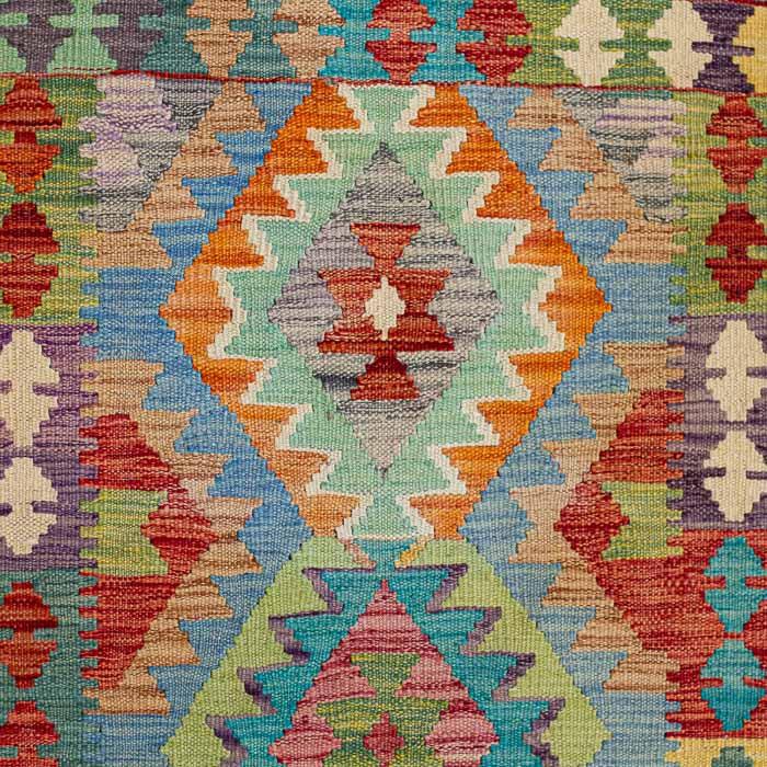 Tapete artesanal Kilim do Afeganistão com grafismos étnicos simétricos sobre trama manual plana de lã natural.