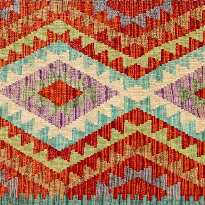 Passadeira artesanal Kilim do Afeganistão apresentando grafismos étnicos simétricos sobre trama manual plana de lã natural.