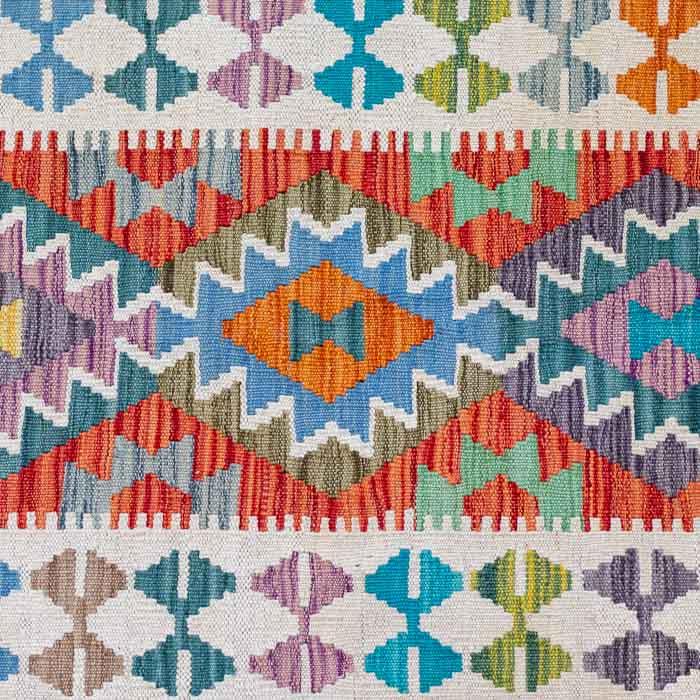 Tapete Kilim afegão feito manualmente com padronagem geométrica em tons diversos e fundo creme.