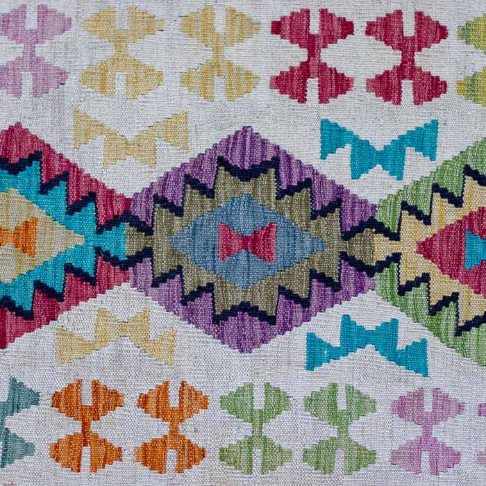 Tapete Kilim afegão tecido manualmente com fundo claro e padrões geométricos coloridos.