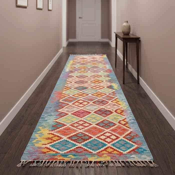 Tapete Kilim afegão oriental de 3 metros em corredor iluminado com banco de couro e plantas, estilo Boho Chic exclusivo.