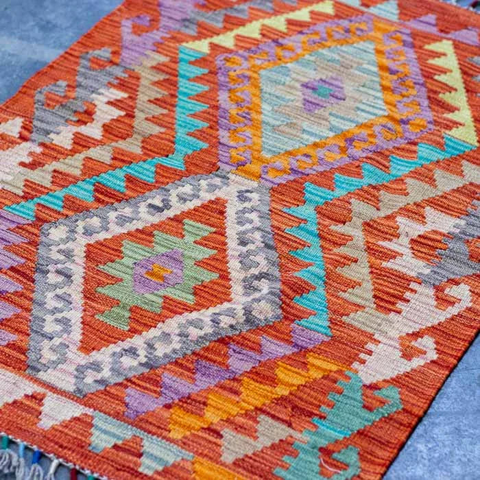 Kilim afegão de 93cm com design orgânico sobre superfície de cimento queimado.