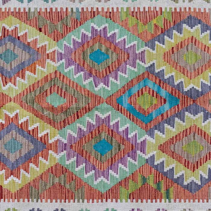 Tapete artesanal Kilim do Afeganistão apresentando grafismos étnicos simétricos sobre trama manual plana de lã natural.