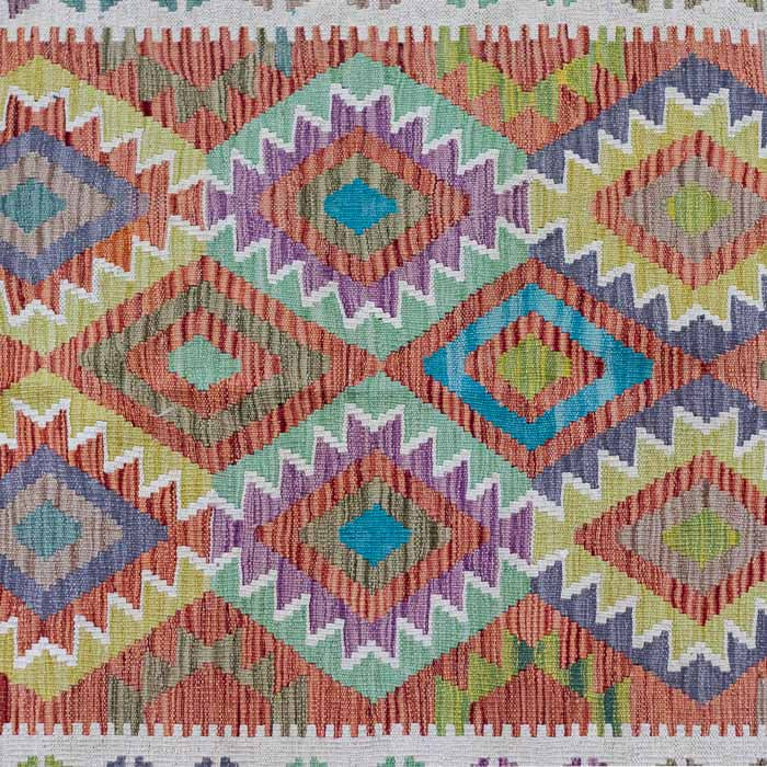 Tapete artesanal Kilim do Afeganistão apresentando grafismos étnicos simétricos sobre trama manual plana de lã natural.