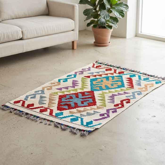 Tapete Kilim afegão tecido à mão com padronagem de losangos coloridos em fundo claro.