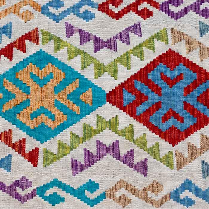 Detalhe da trama plana artesanal de tapete Kilim pequeno em fibras de lã e algodão.