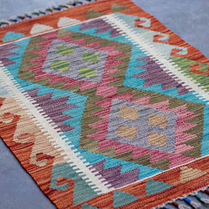 Decoração rústica de luxo com pequeno tapete Kilim colorido sobre piso de madeira clara.