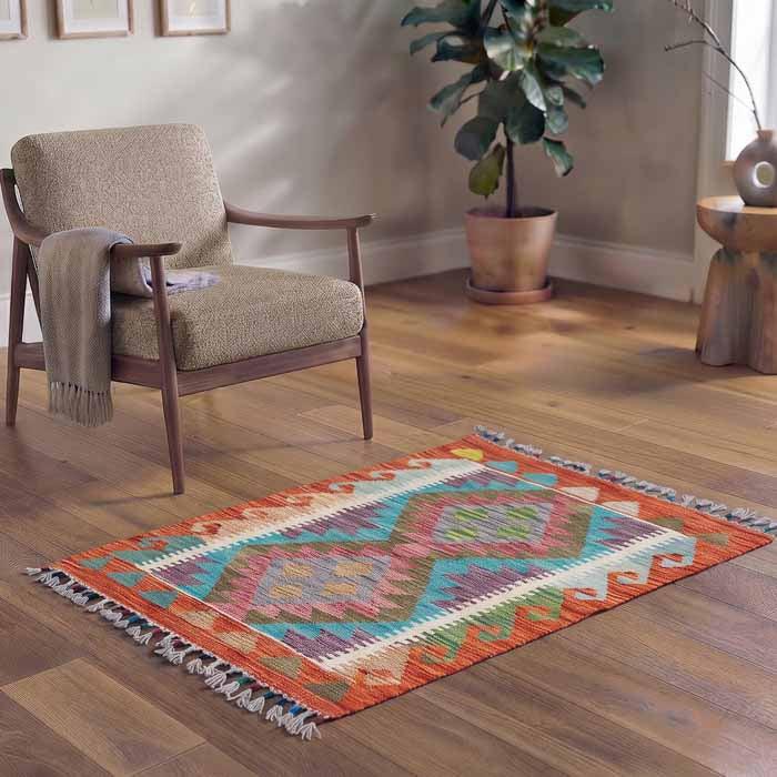 Tapete artesanal de 90cm do Afeganistão posicionado em ambiente Boho com poltrona de linho e cestaria de vime.