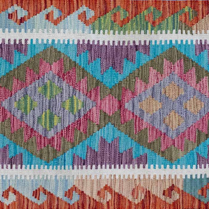 Passadeira étnica Kilim afegã com losangos multicoloridos e franjas artesanais em plano detalhado.