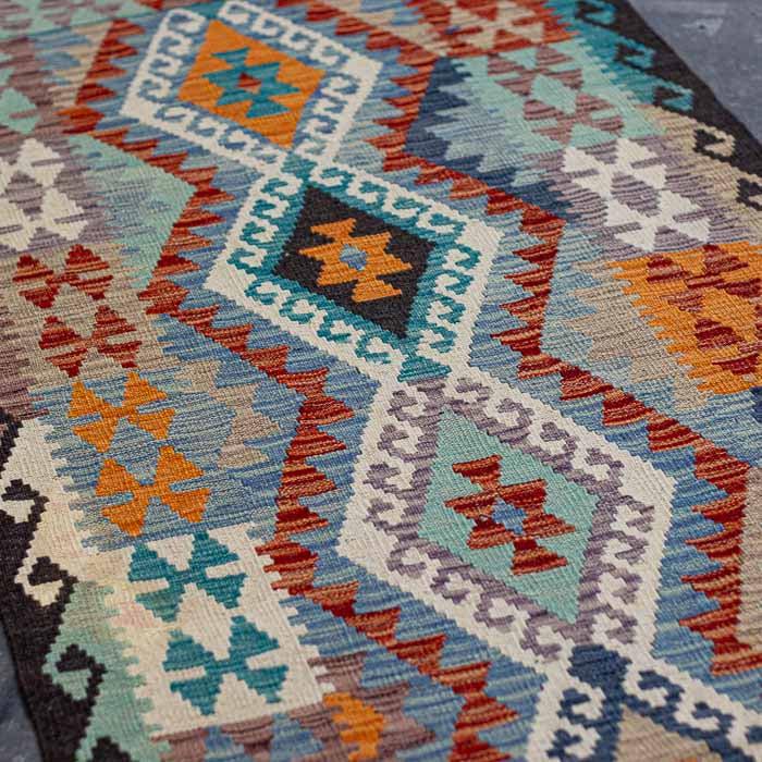 Composição de interiores de alto padrão com tapete Kilim rústico vibrante posicionado em ambiente de estar.