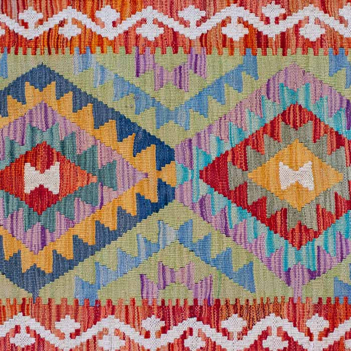 Tapete artesanal Kilim do Afeganistão com grafismos geométricos étnicos coloridos e técnica de tecelagem plana manual.