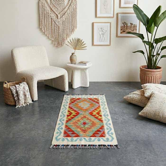 Tapete Kilim afegão tecido à mão com padronagem de losangos coloridos e bordas azuis.