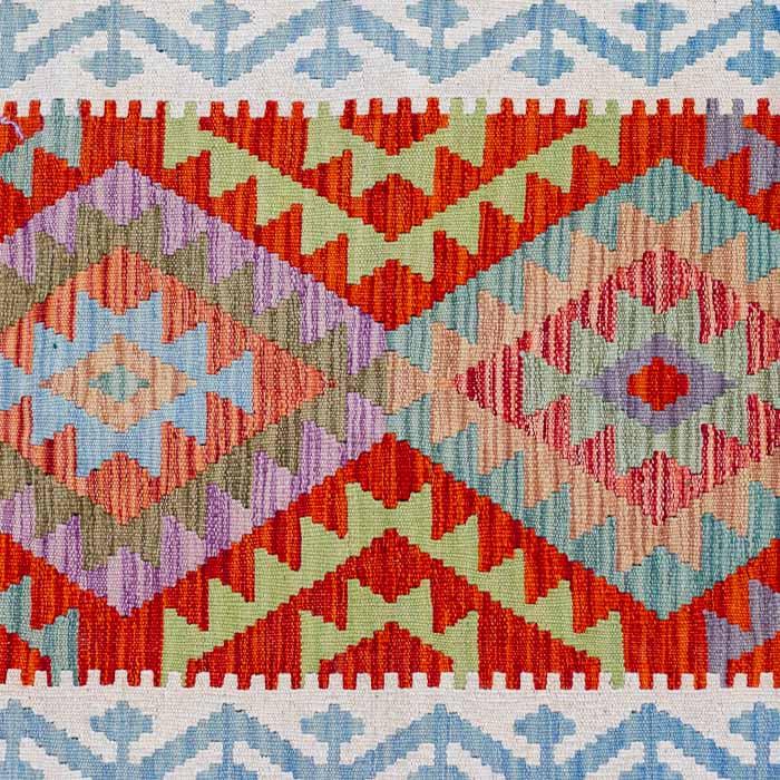 Detalhe da trama plana artesanal de tapete Kilim pequeno em fibras de lã e algodão.