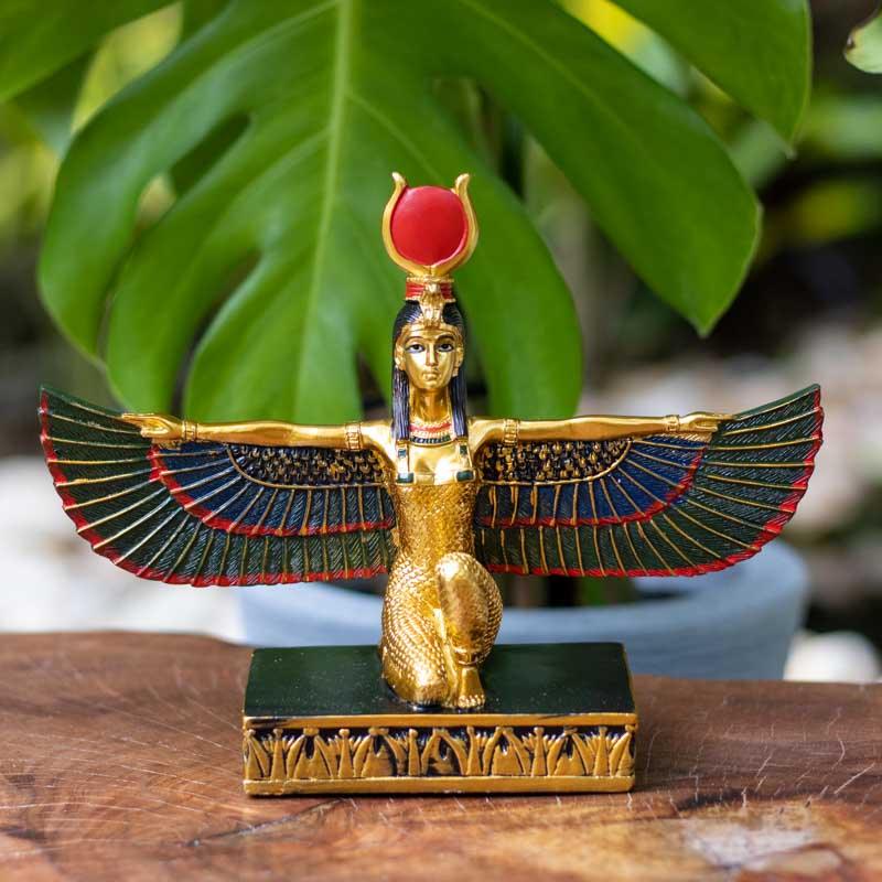 Revelando a beleza e o mistério, a escultura da deusa Isis Alada com asas abertas e o sol resplandecente ao fundo.