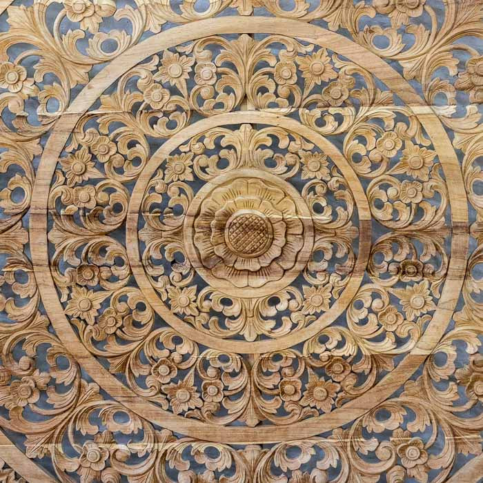 Painel mural decorativo em madeira maciça com mandala floral circular entalhada à mão para cabeceira de cama.