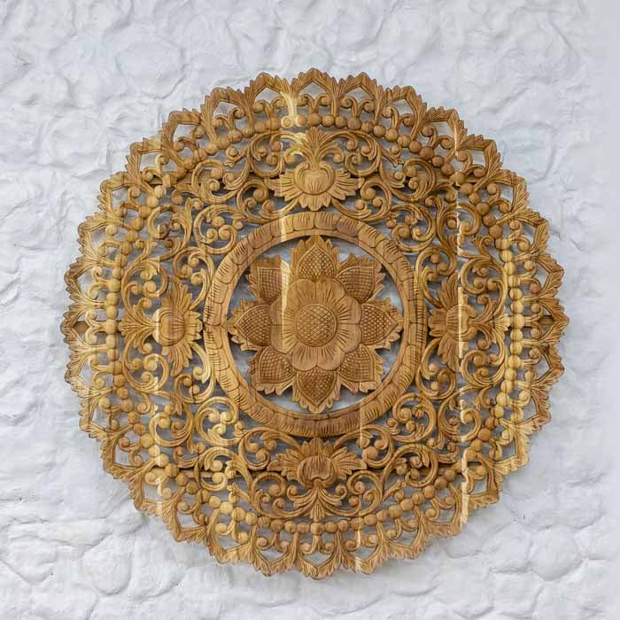 Mandala floral de Bali em madeira nobre instalada sobre parede de fundo claro como cabeceira.