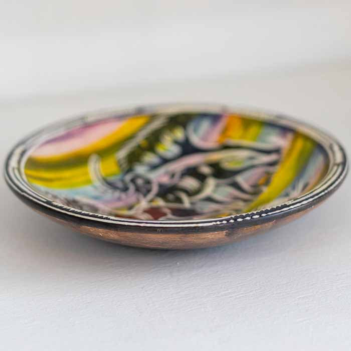 Tigela rasa decorativa com fundo amarelo vibrante e silhuetas de animais da savana esculpida à mão. 