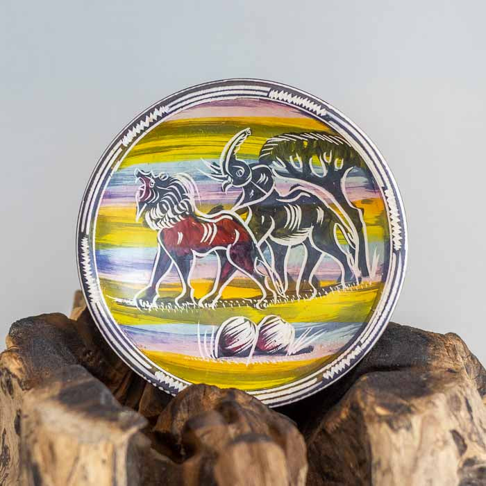 Visão superior de tigela redonda em pedra sabão com pintura colorida de leão e elefante em estilo artístico africano. 
