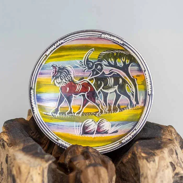 Visão superior de tigela redonda em pedra sabão com pintura colorida de leão e elefante em estilo artístico africano. 