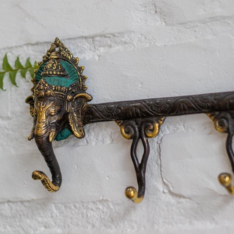Cabideiro de bronze com 4 ganchos e detalhes de deidade hindu para organização de ambientes sofisticados.