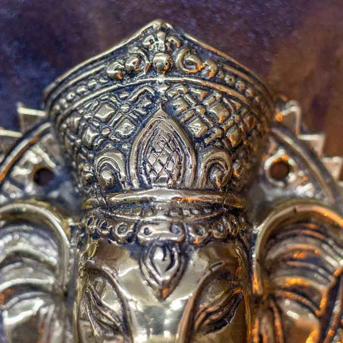 Arte hindu feita à mão em bronze representando Ganesha com coroa dourada e expressão serena, usada como puxador de móveis ou porta, produzida em Bali. 
