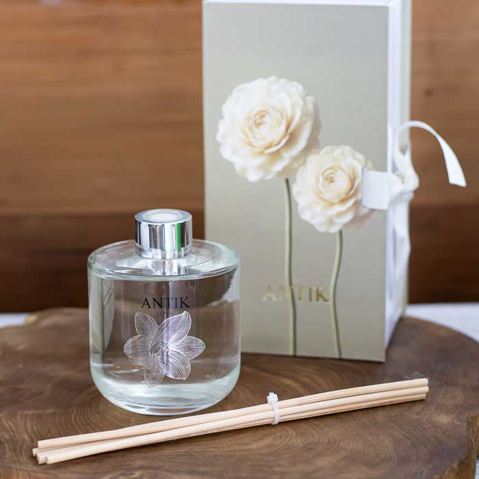 Detalhe da flor gravada no frasco transparente do aromatizador Antik com varetas condutoras. 