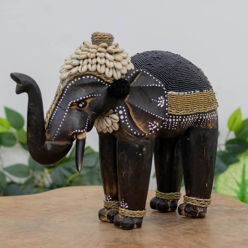 Escultura artesanal de elefante em madeira decorada com búzios.