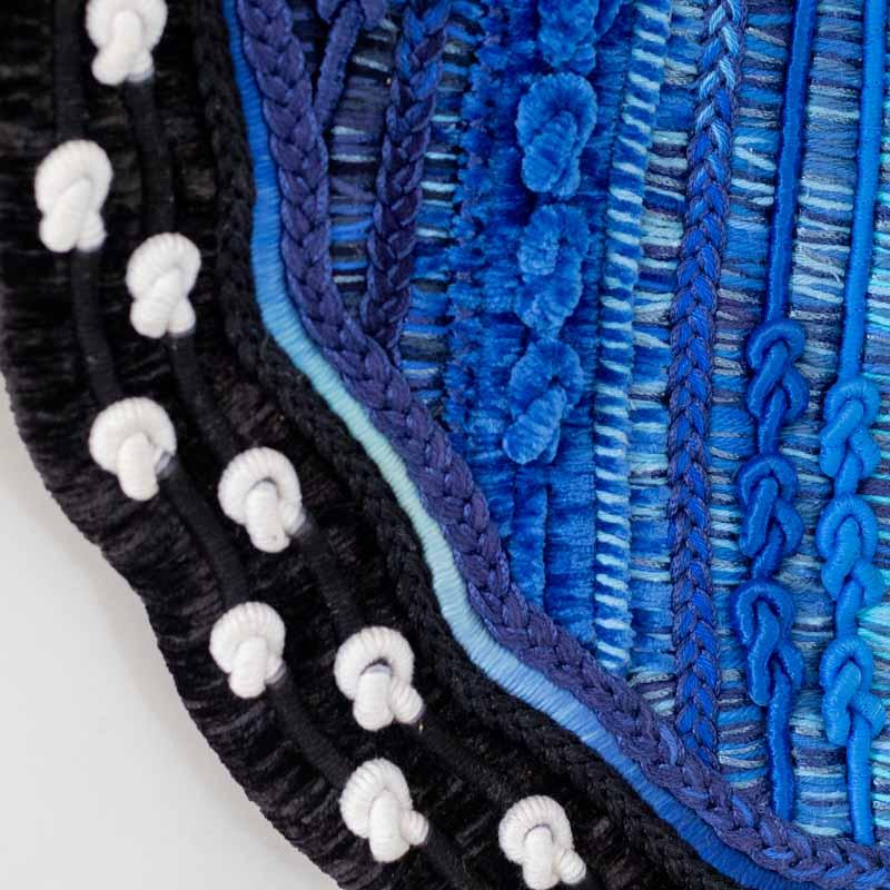 Detalhe da trama têxtil em algodão reciclado e veludo, criando um padrão complexo de azul e preto na asa de borboleta Morpho.