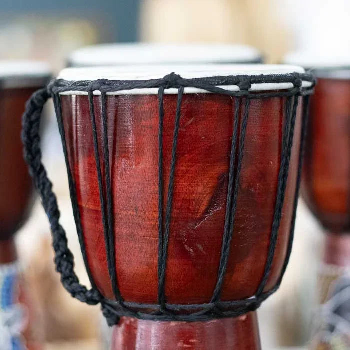 Tambor decorativo com corpo em madeira esculpida e superfície pintada com padrões tradicionais de origem aborígene 