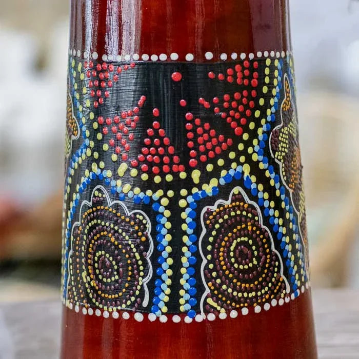 Detalhe do tambor djembê feito à mão em madeira com arte animal pintada, representando o diálogo entre culturas africana e balinesa. 