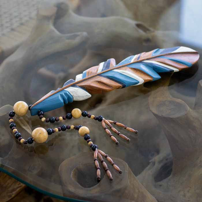 Colar de mesa artesanal em madeira com formato de pena indígena colorida.