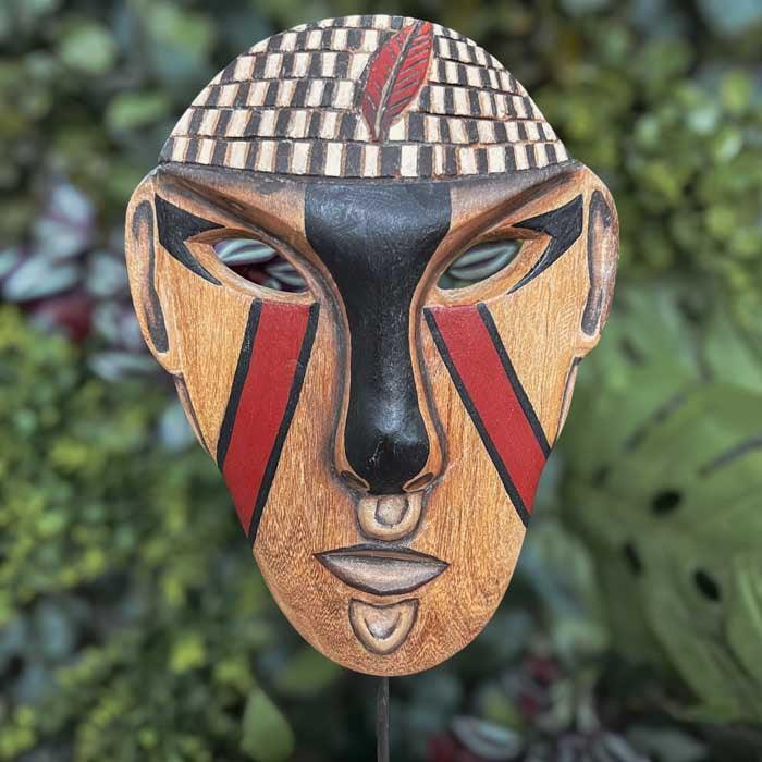 Máscara indígena artesanal da etnia Potiguara esculpida em madeira, apresentada em base decorativa com pintura tradicional.