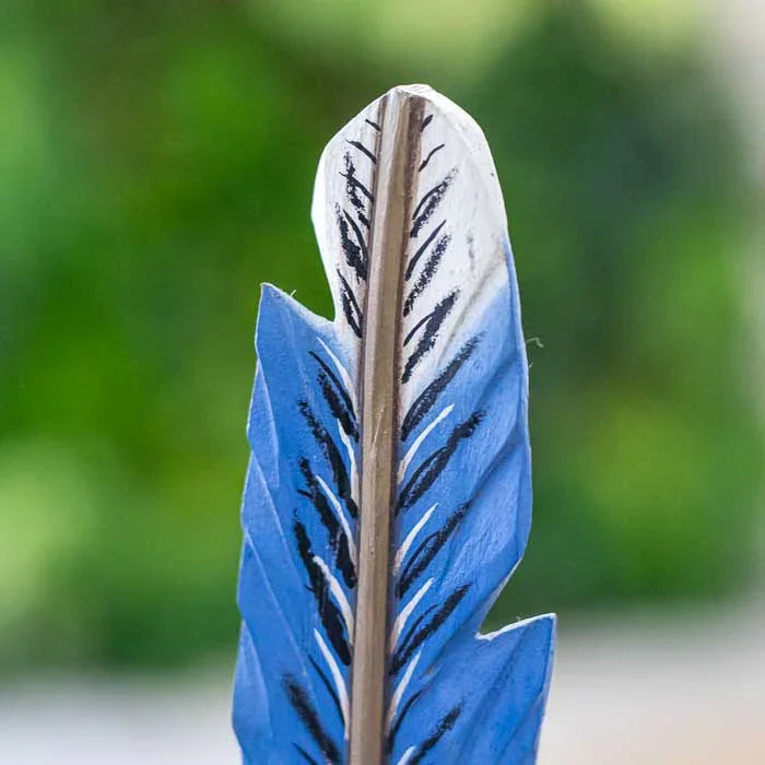 Objeto decorativo com forma de pena esculpida à mão em madeira natural. 