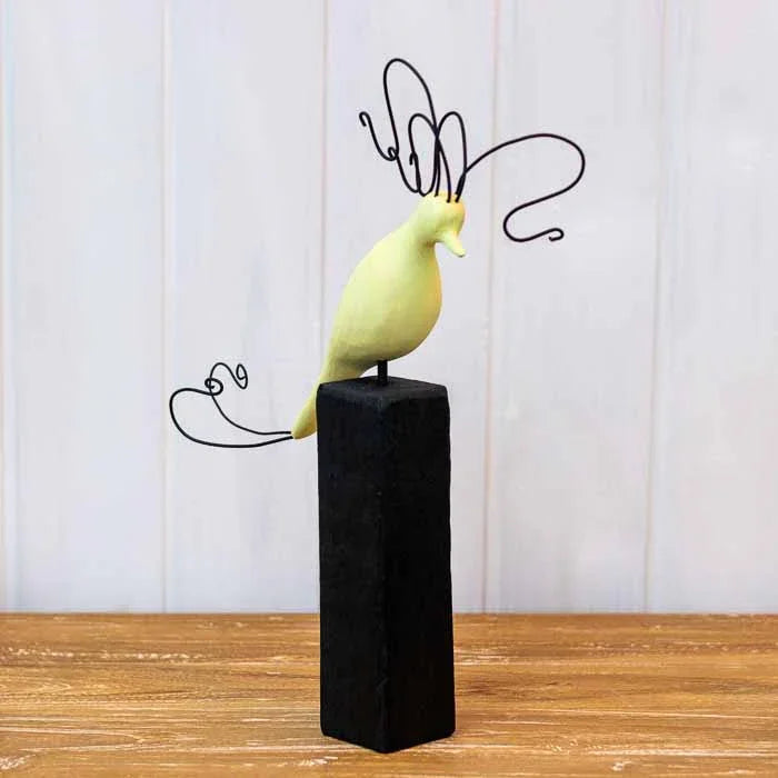 Escultura de pássaro estilizado roxo com crista de metal em espiral sobre base de madeira preta. 