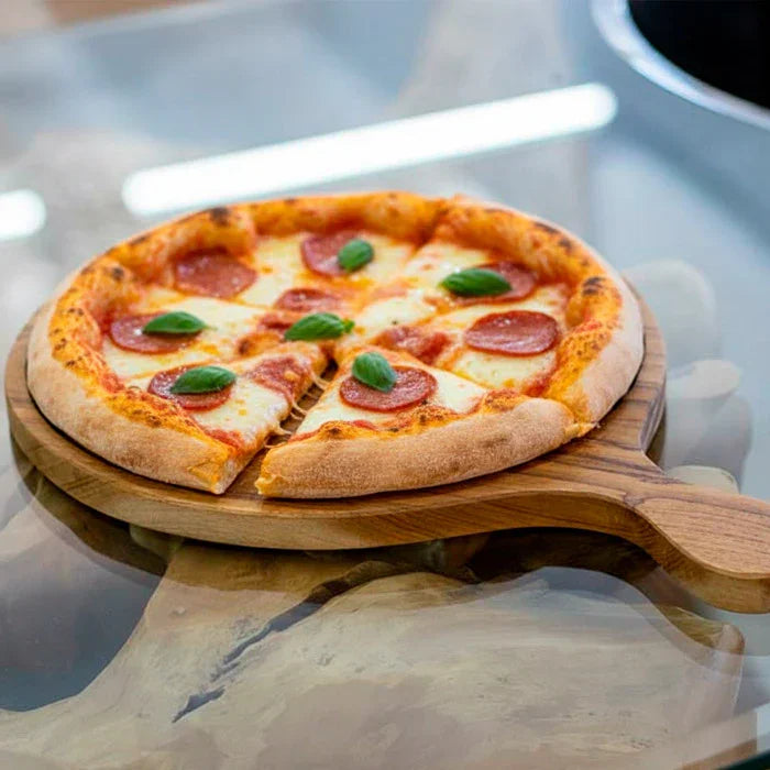 Tábua artesanal feita à mão em madeira teca de Bali, com acabamento natural e cabo anatômico, ideal para servir pizza ou usar como peça decorativa.