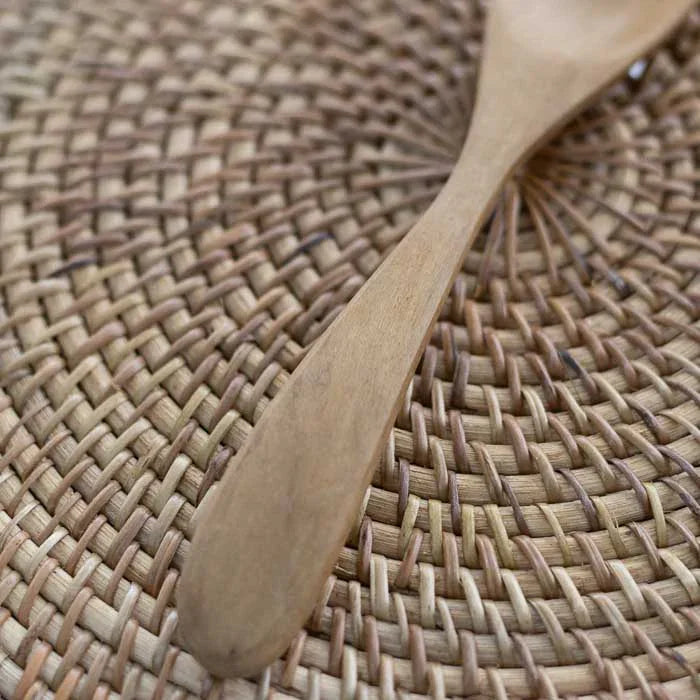 Colher de pau em teca originária de Bali com cabo anatômico e textura natural usada para preparar alimentos com leveza e segurança.