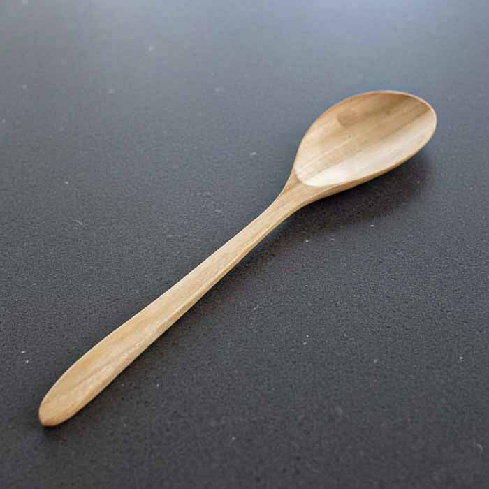 Colher grande esculpida manualmente em madeira teca de Bali com forma ergonômica e superfície suave perfeita para uso diário na culinária.