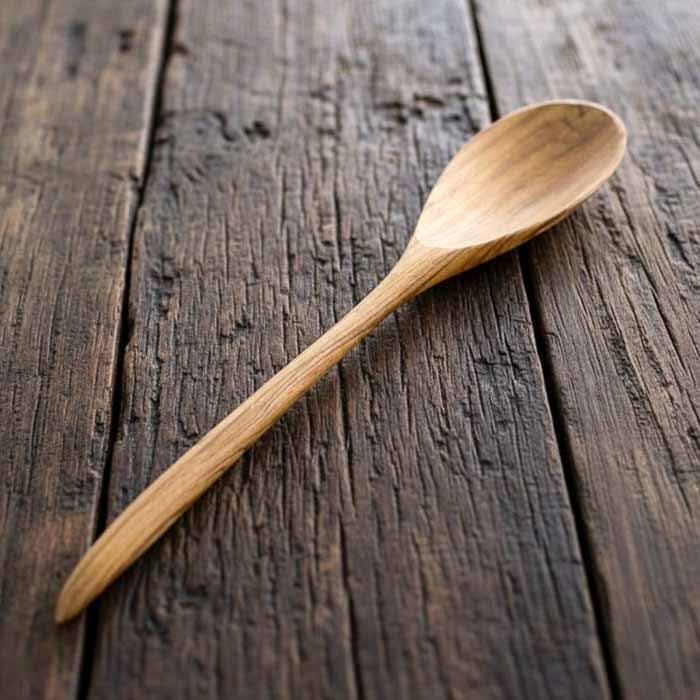 Colher de pau longa de teca produzida manualmente em Bali com superfície suave e veios naturais indicada para cozinhar sem danificar panelas.