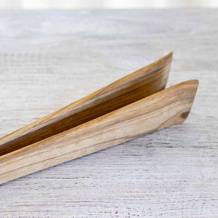 Detalhe da textura e veios naturais de pegador de madeira clara para saladas.